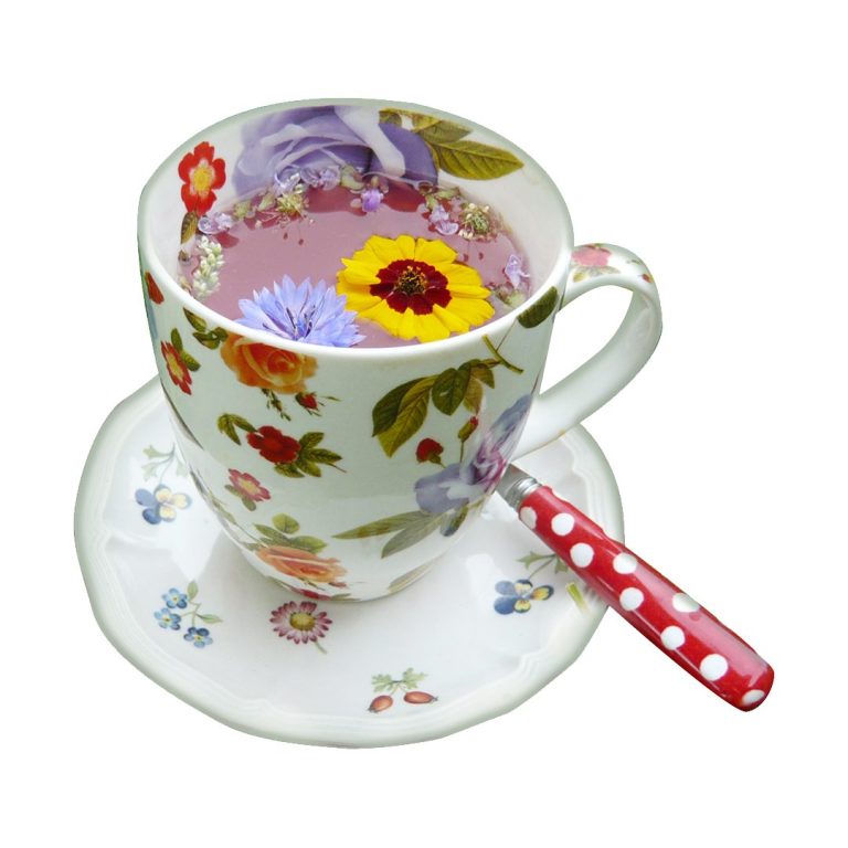 Teetasse mit bunten Blumen auf einer Untertasse und einem gepunkteten Löffel.