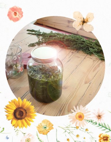 Ein Glas mit grünem Kräuterextrakt auf einem Holztisch, umgeben von Blumen.